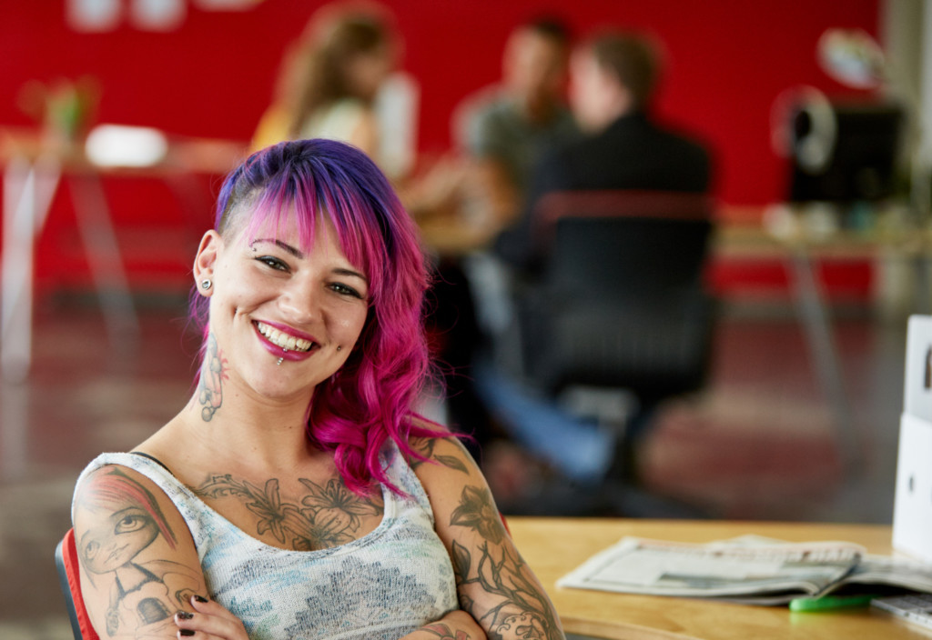 Lachende junge Designerin mit pink gefärbte Haare