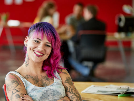 Lachende junge Designerin mit pink gefärbte Haare