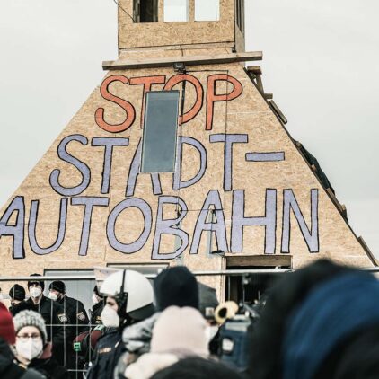 Nahaufnahme der Pyramide des Lobau-Protests in der Hausfeldstraße. Auf ihr steht in großer und bunter Schrift "Stop Stadtautobahn".