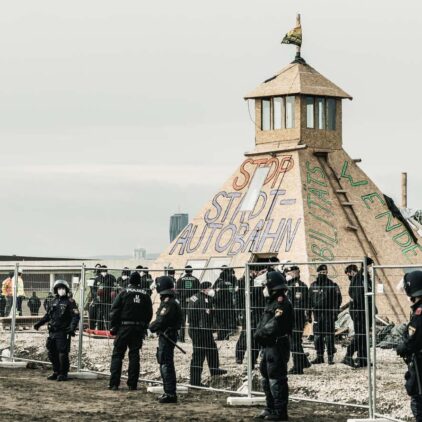 Hunderte Polizist:innen bewachen den selbstgebauten Unterstand im Camp in der Hausfeldstraße während dieser abgerissen wird und hunderte Menschen demonstrieren.