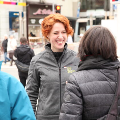 Straßenszene mit einer lächelnden jungen Frau im Gespräch