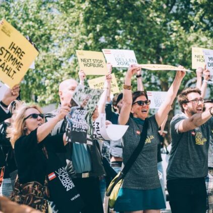 Foto von begeisterten Anhänger:innen von VdB, die Plakate in die Luft halten