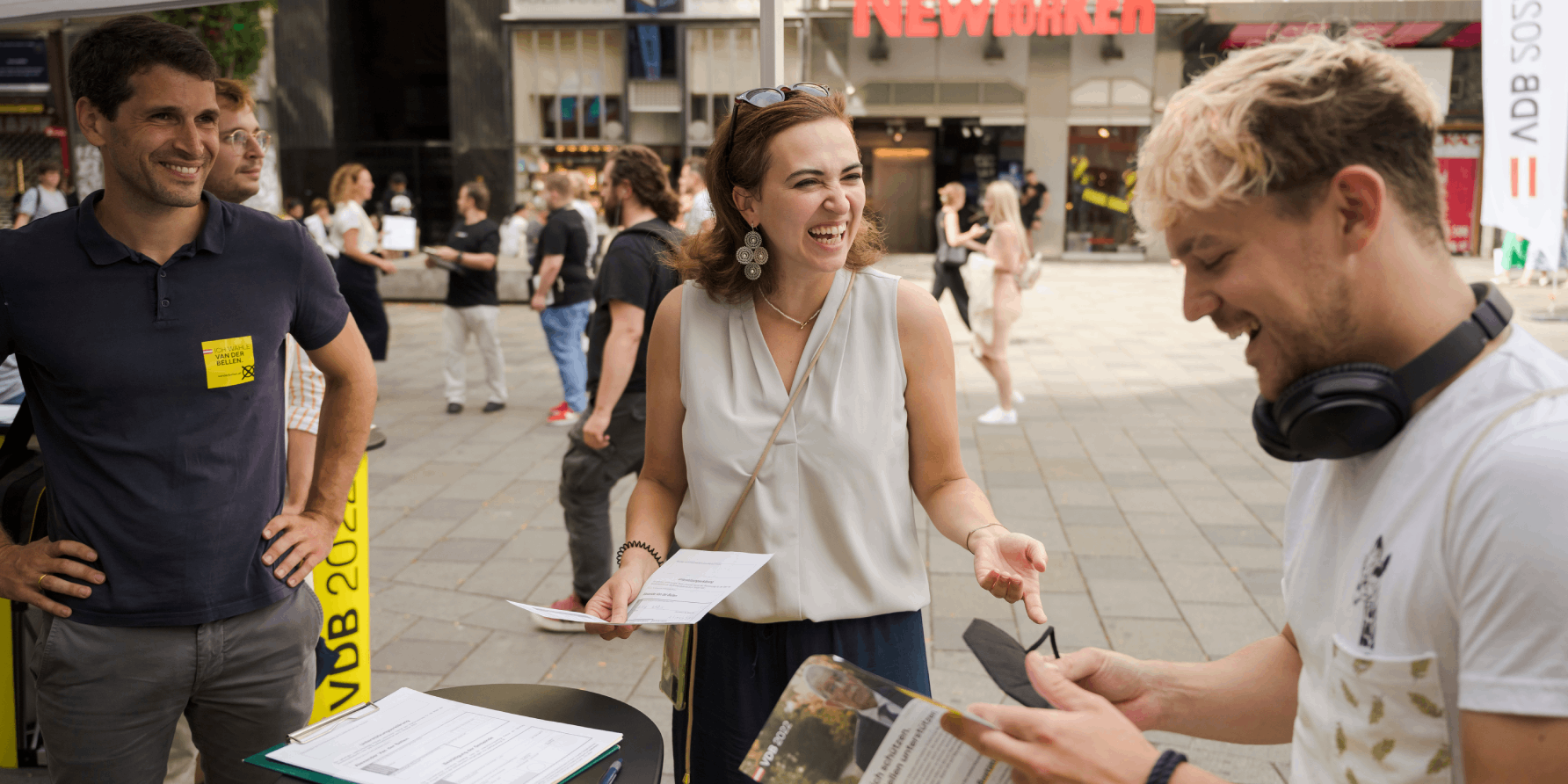 Wahlkampfstandl VdB, Alma Zadic und ein junger Mann lachen