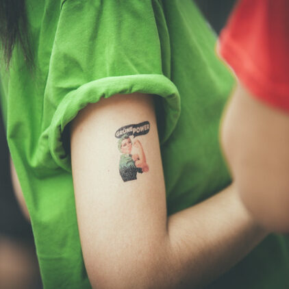 Foto eines Oberarmes mit einem Tattoo in Form einer Frau die die Faust hebt und der Schrift "Grüne Power"