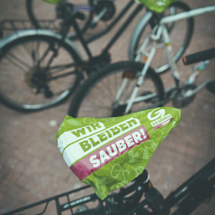 Foto eines Fahrradsattels mit einem grünen Überzug mit der Aufschrift "Wir bleiben sauber"