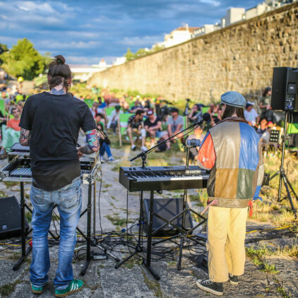 Foto einer Band beim Konzert, im Hintergrund sieht man das Publikum
