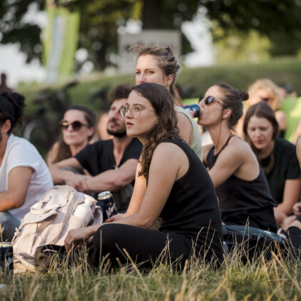Eine Gruppe von jungen Menschen lauscht einem Konzert im Sommer
