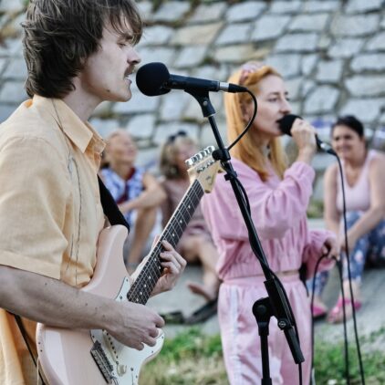 Ein junger Mann mit Gitarre und eine junge Frau, die singt