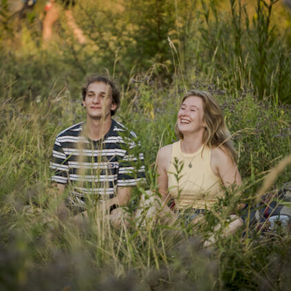 Zwei junge Menschen sitzen im Gras